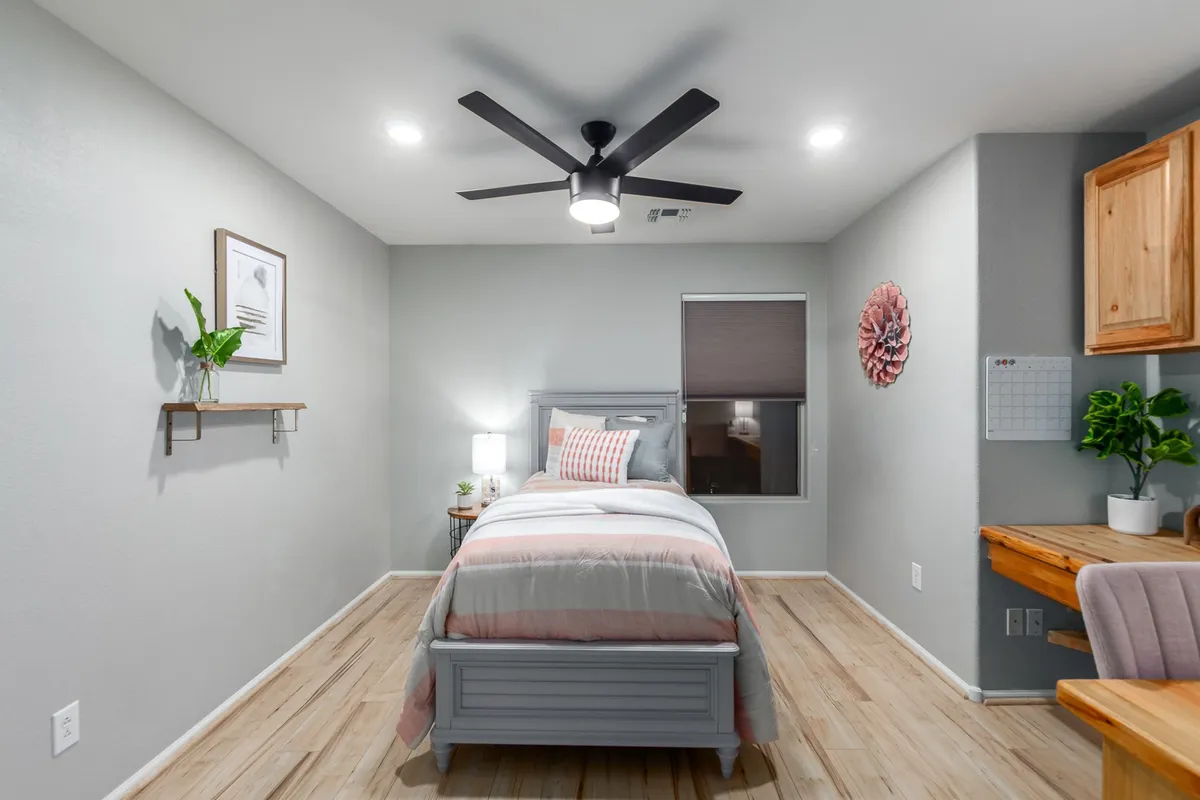 A tranquil bedroom with a bed, ceiling fan, desk area, and a window that lets in natural light. The setup is ideal for both relaxing and working, with a workspace that caters to remote workers or solo travelers.