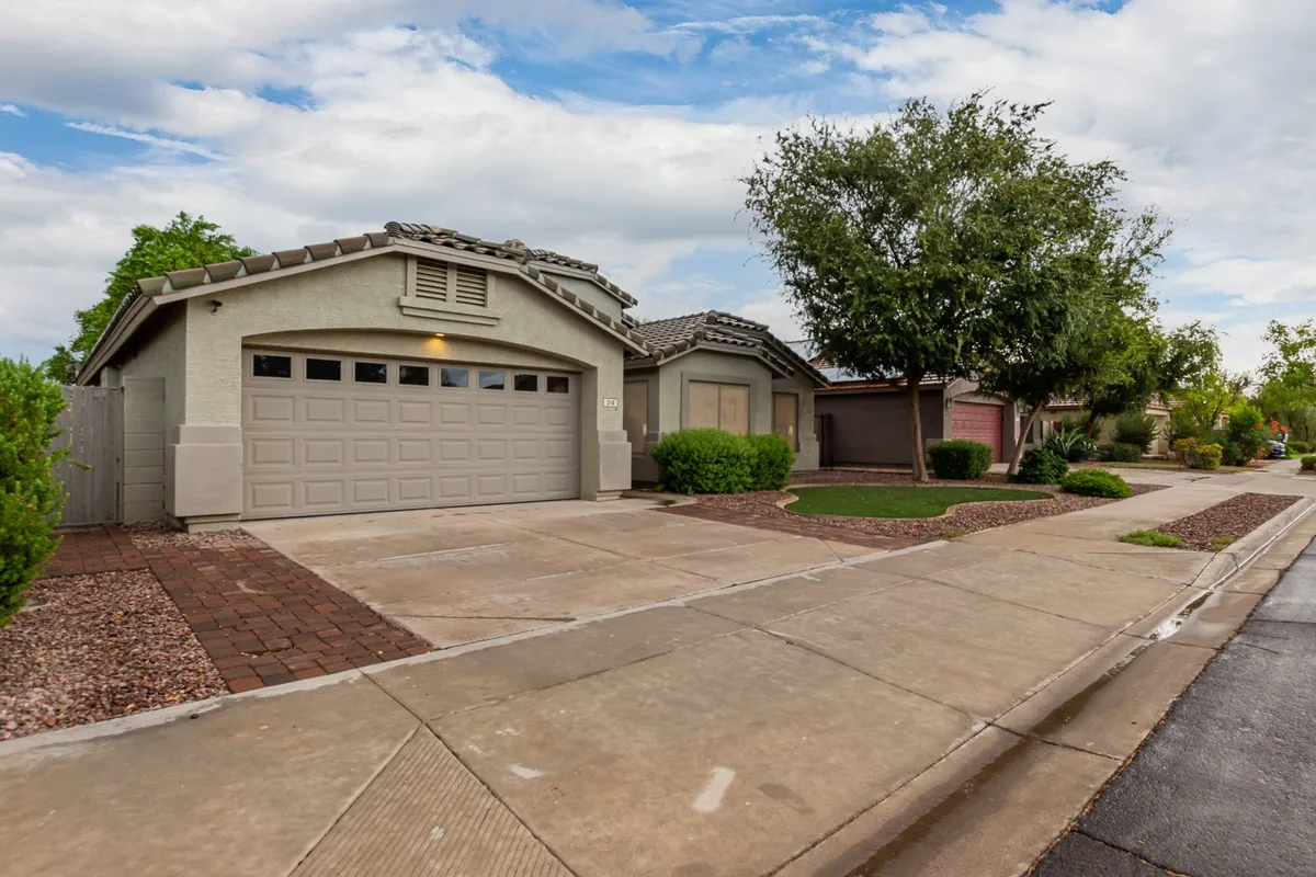 This exterior image showcases the home's front yard with a well-maintained driveway, garage door, and inviting landscaping. The open space hints at a welcoming neighborhood ideal for walking dogs, and the visible pathways suggest easy access to local walks.